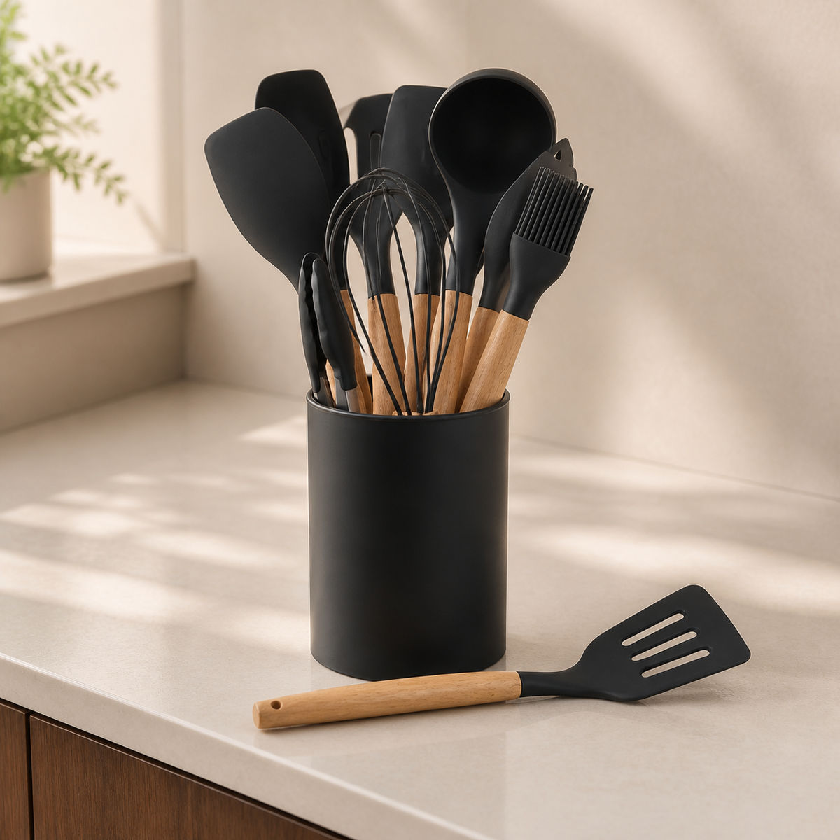 Black silicone kitchen utensils with wooden handles on a cream countertop
